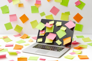 A laptop screen covered with vibrant sticky notes in a creative office setting.